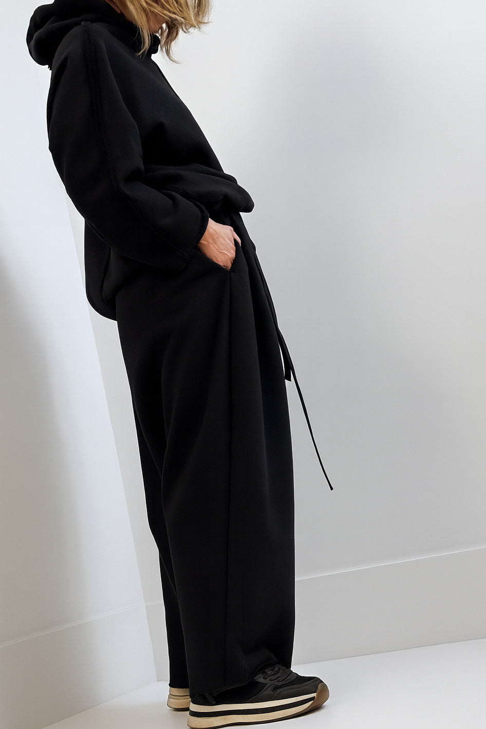 Person wearing a black outfit with wide-leg pants against a white background