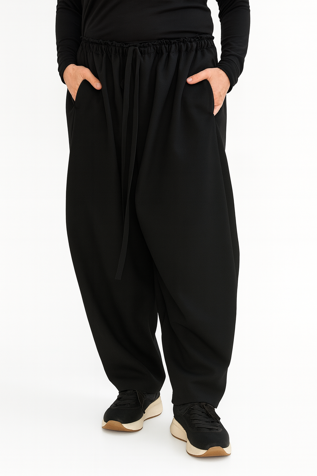 Black harem pants worn by a person on a white background