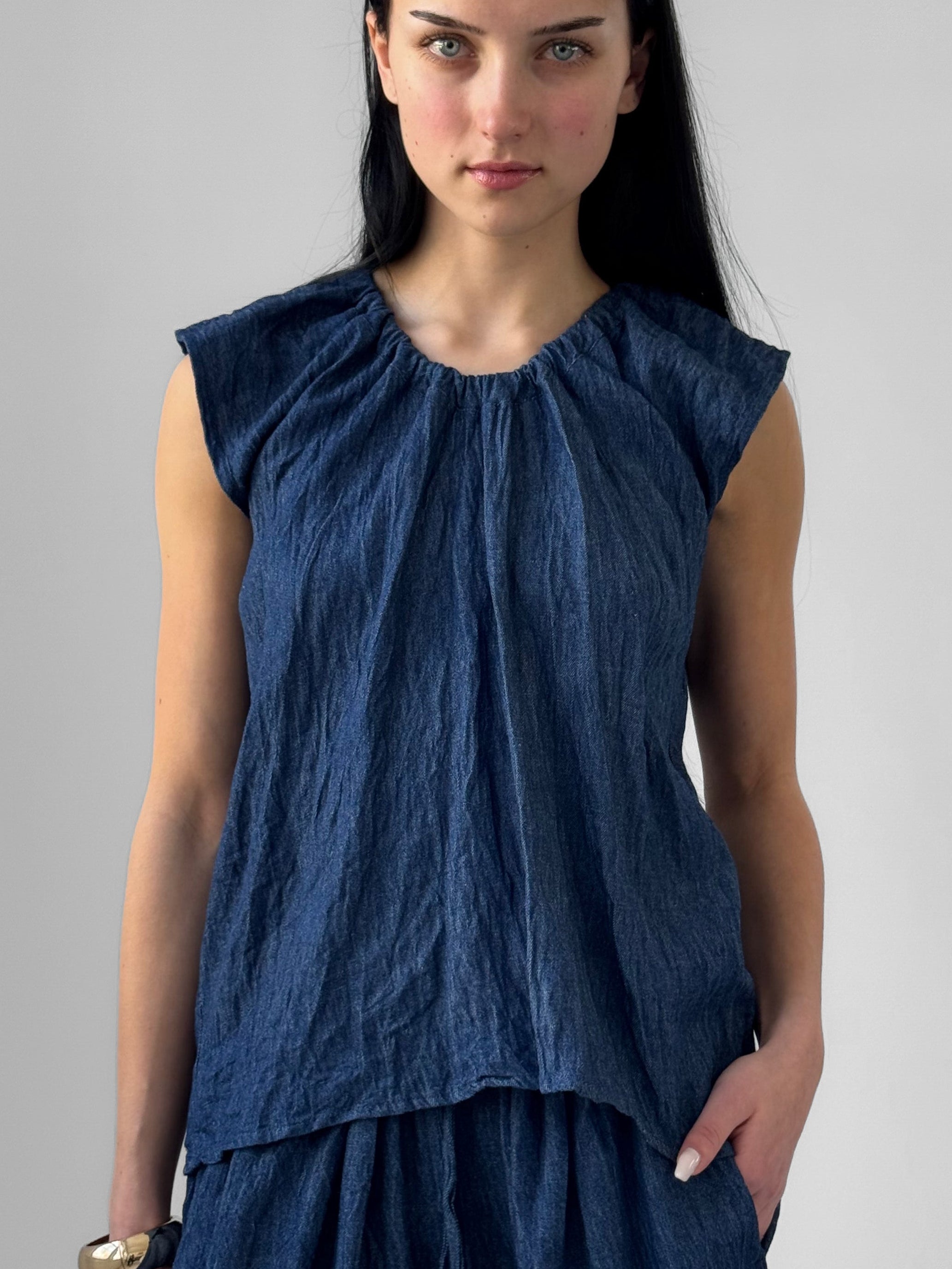 Woman wearing a blue sleeveless top and skirt against a gray background