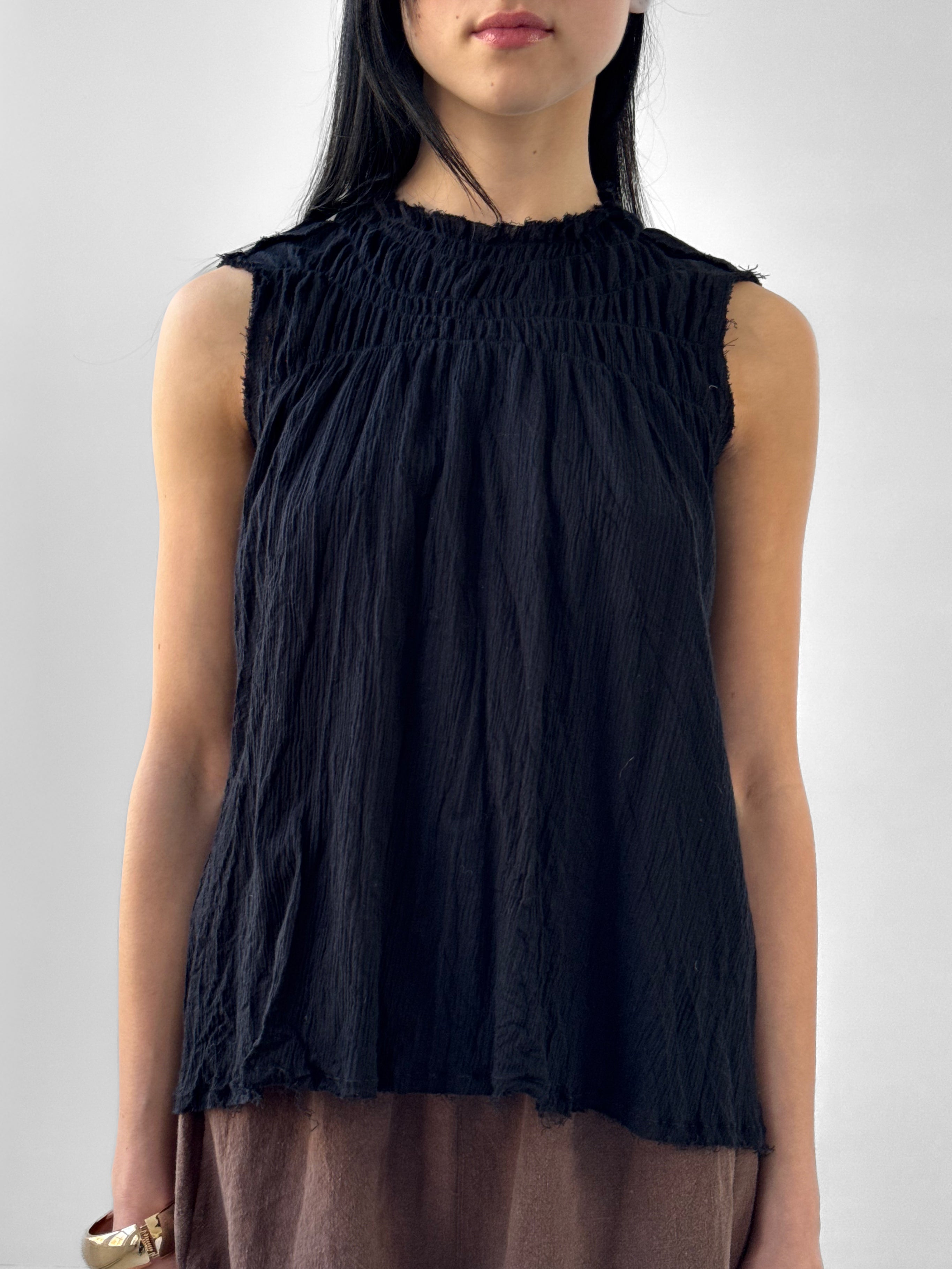Black sleeveless top worn by a person on a plain background
