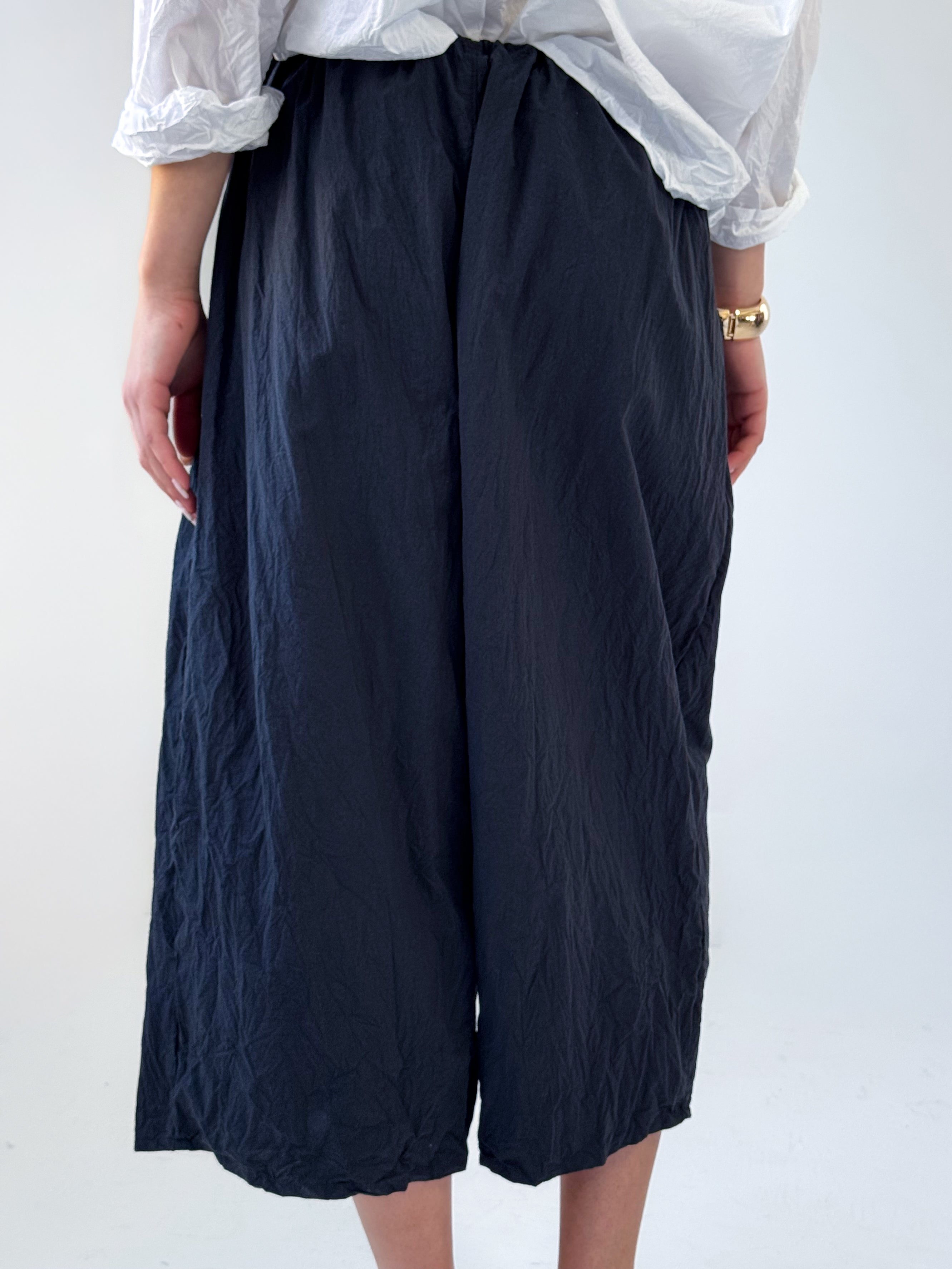 Noor drop crotch pants in crumpled black cotton with drawstring waist and relaxed cropped silhouette