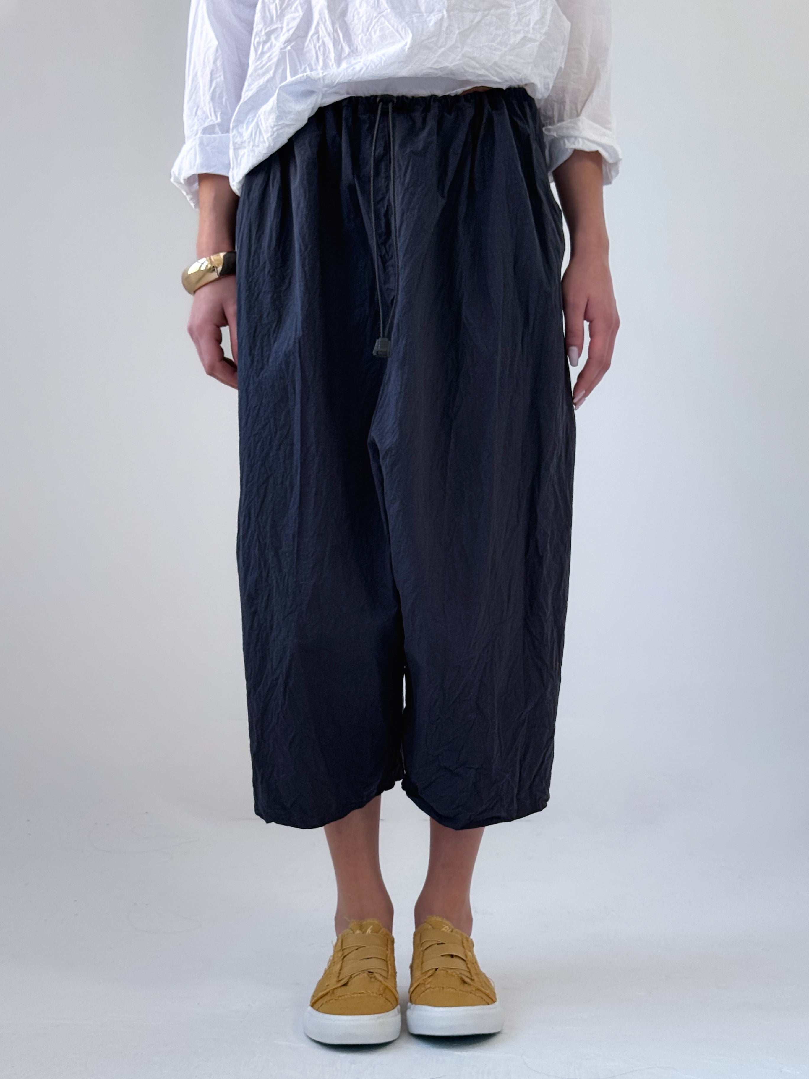 Noor drop crotch pants in crumpled black cotton with drawstring waist and relaxed cropped silhouette