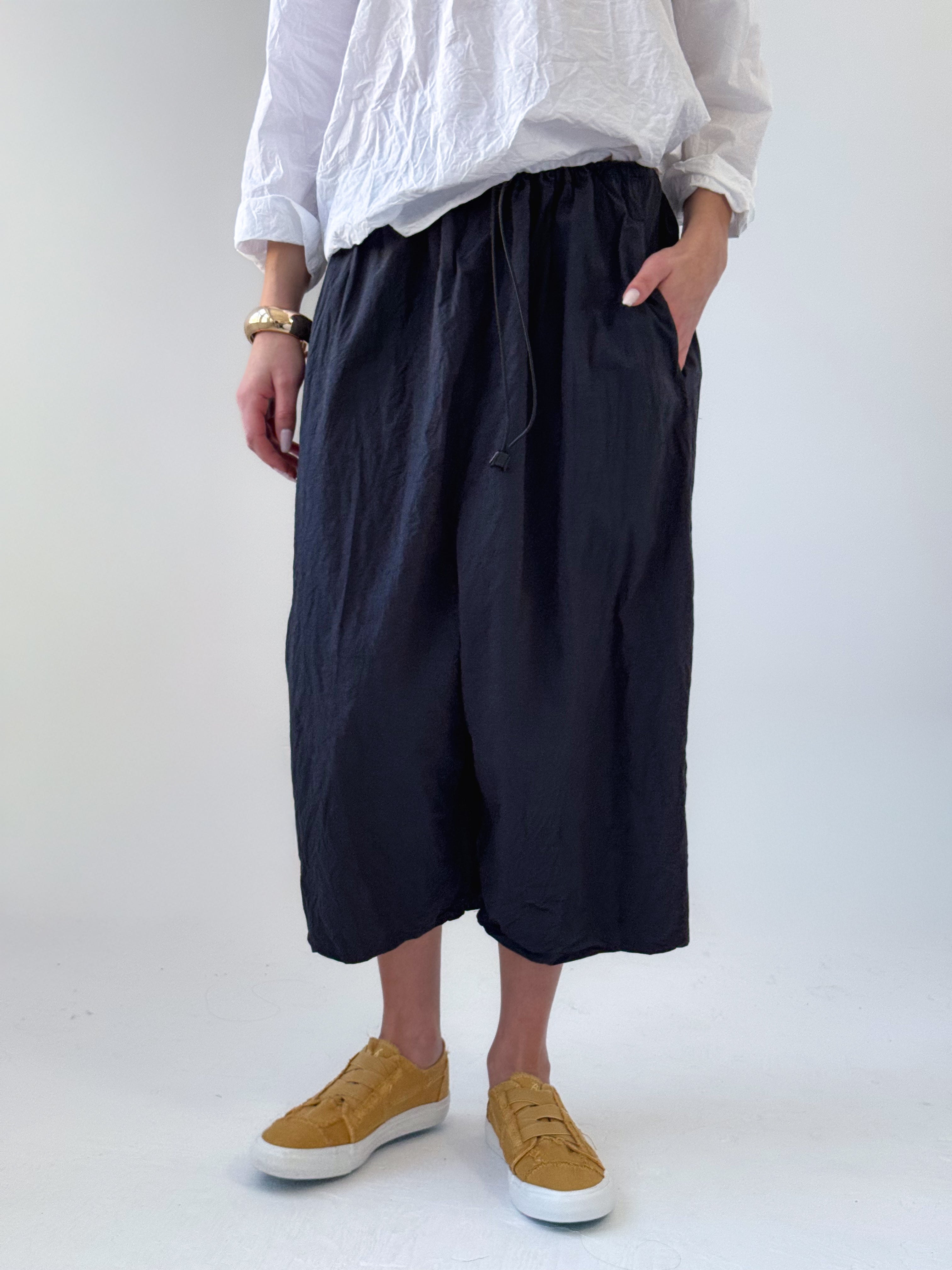 Noor drop crotch pants in crumpled black cotton with drawstring waist and relaxed cropped silhouette
