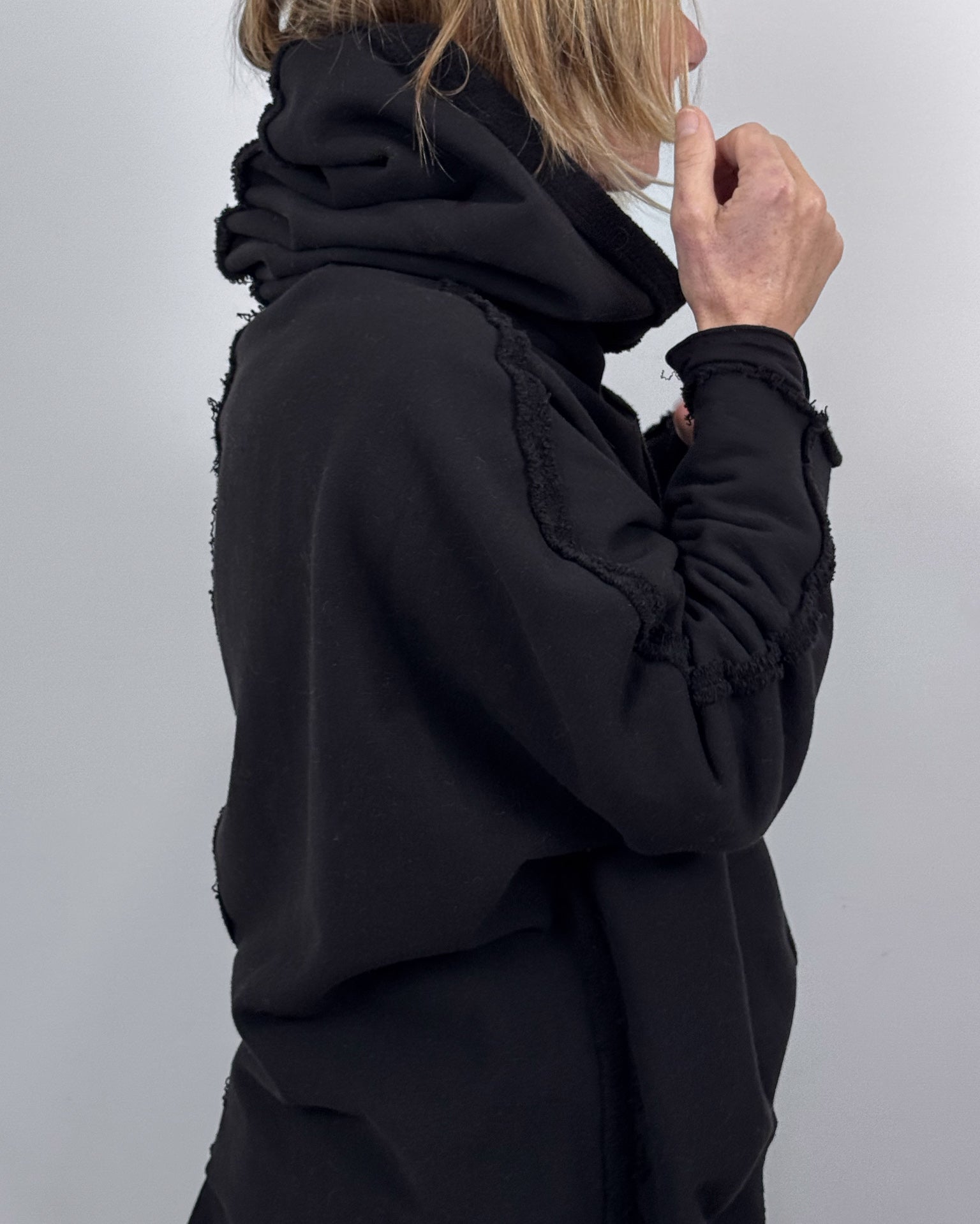 Person wearing a black hoodie against a plain background
