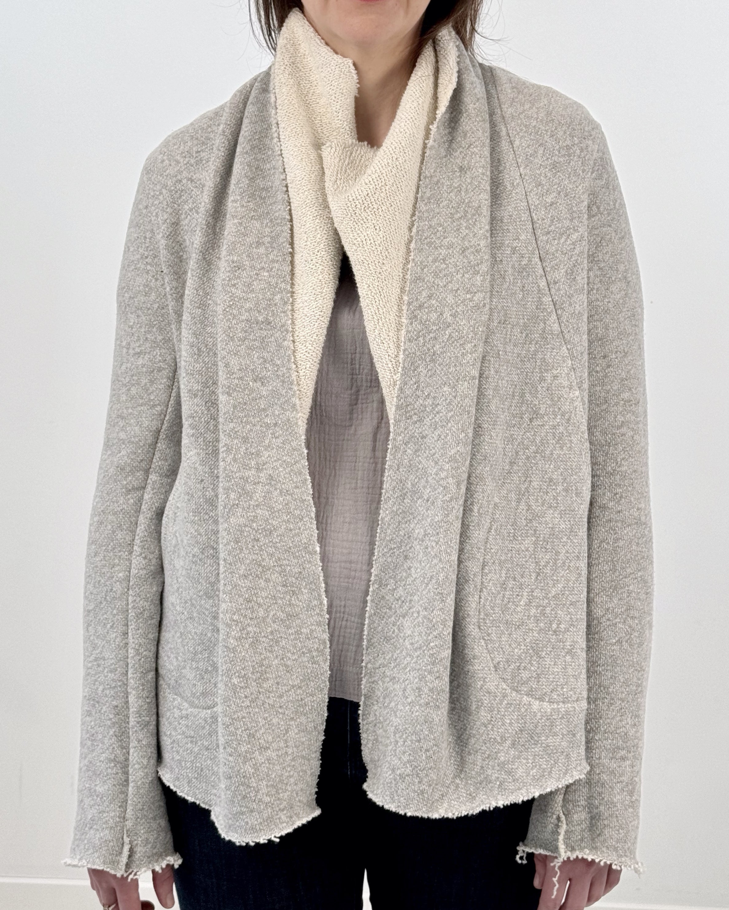 Woman wearing a gray and white wrap jacket against a white background
