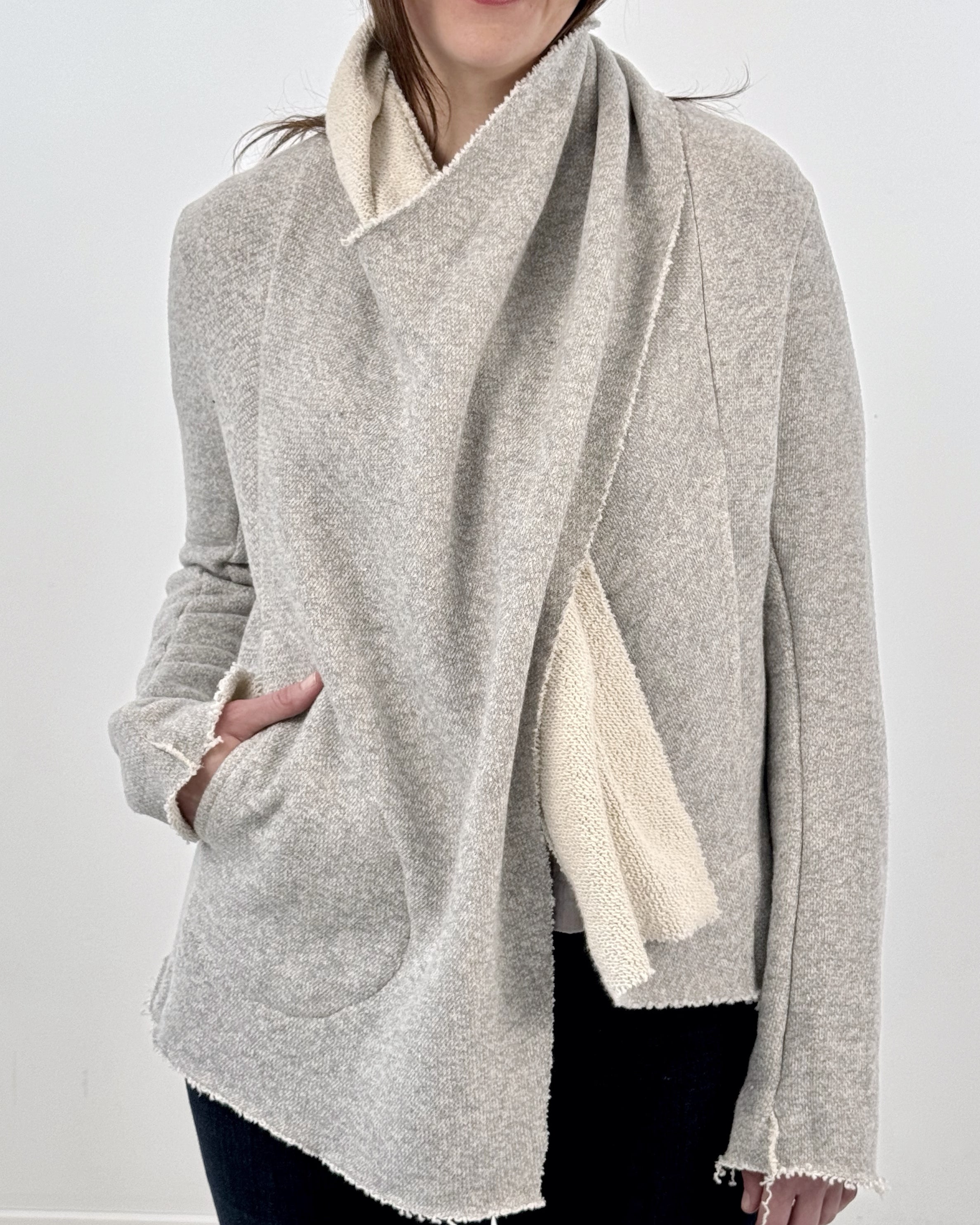 Woman wearing a gray and white wrap jacket against a white background