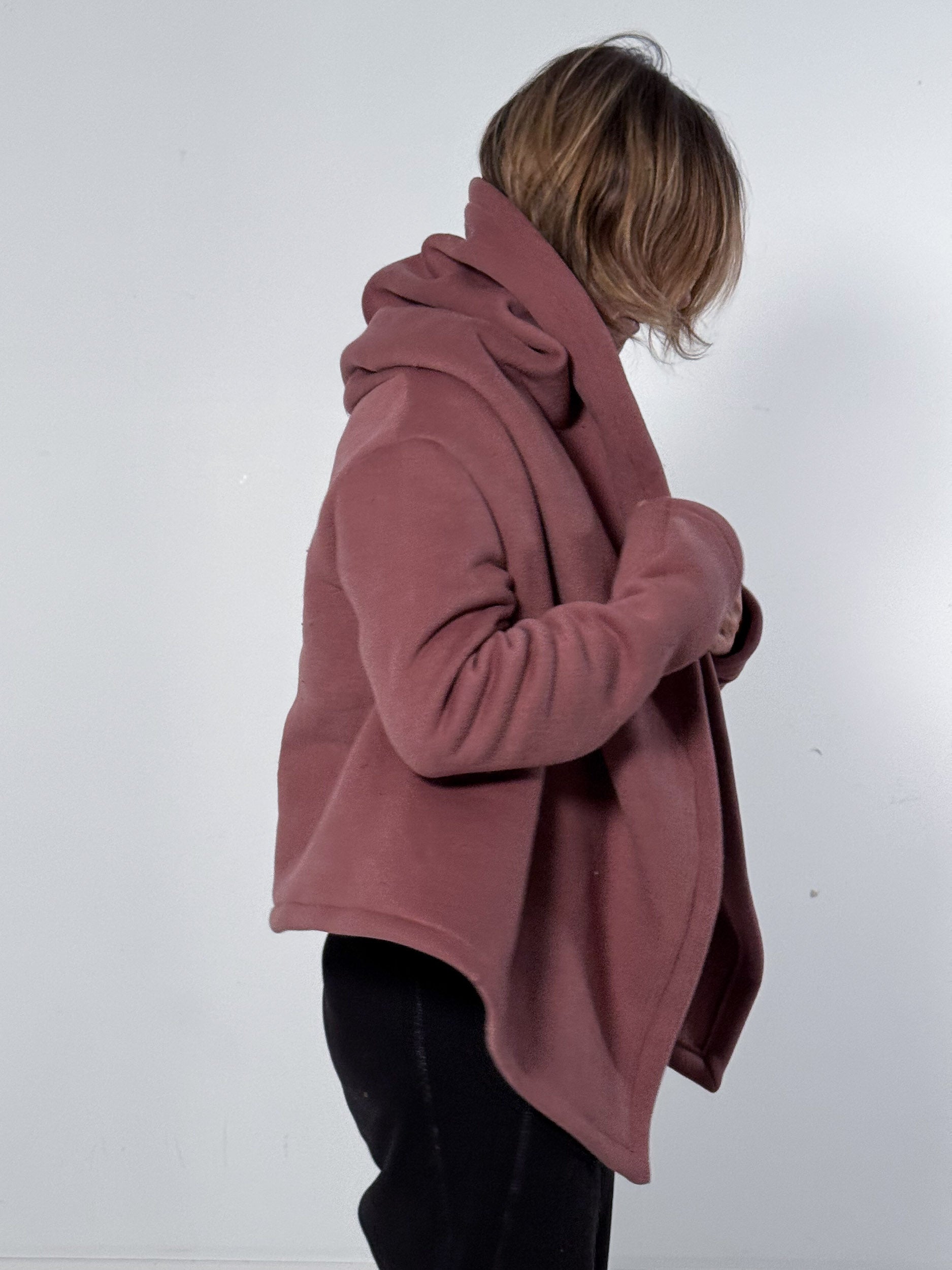 Person wearing a mauve coat against a white background