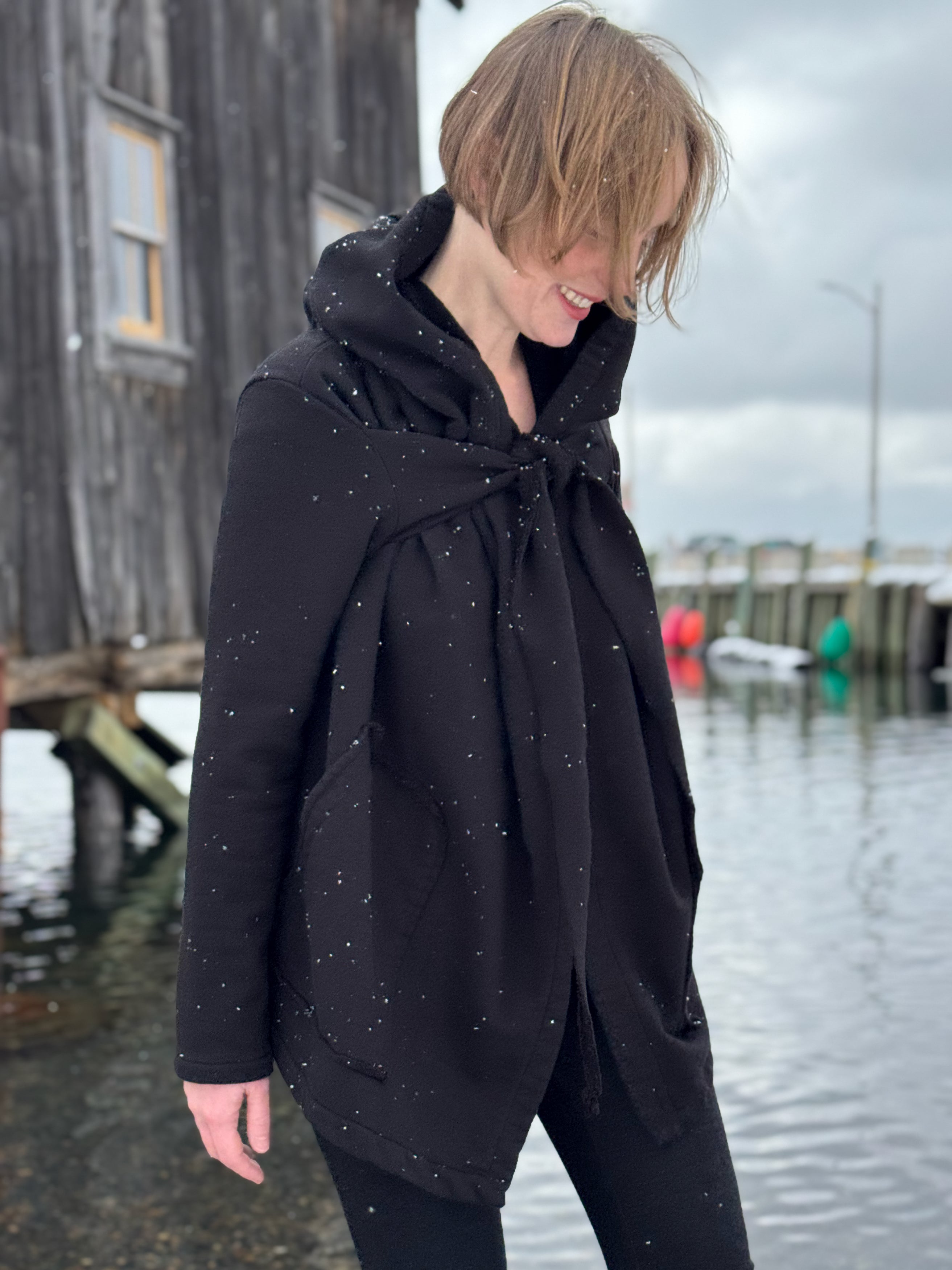 Person wearing a black coat with a hood in a snowy outdoor setting