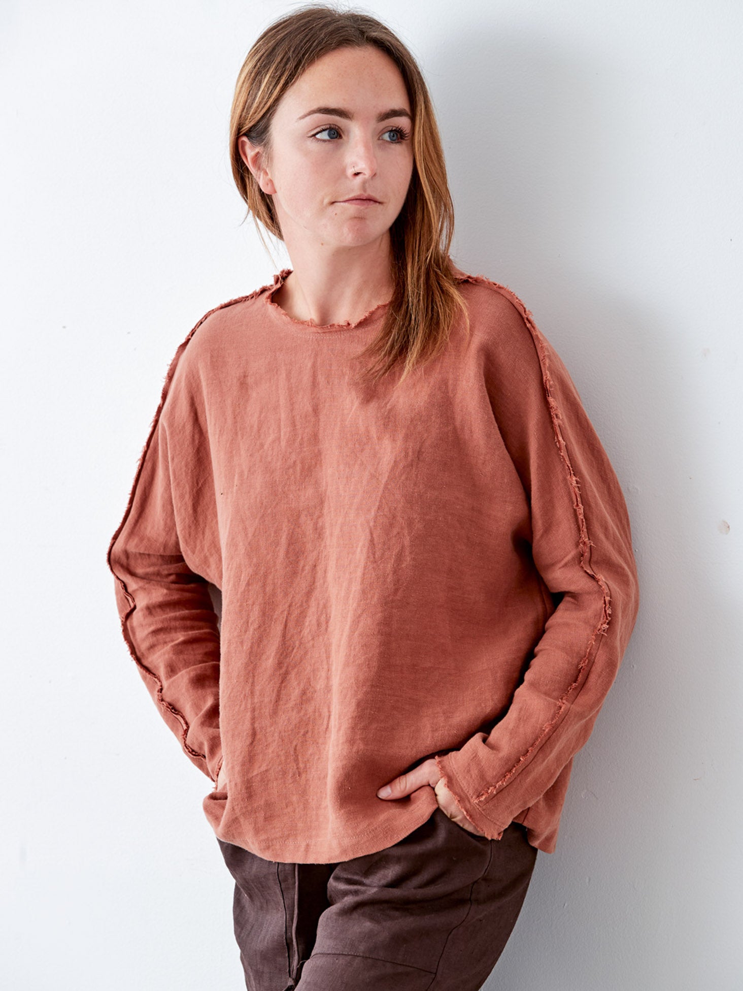 Person wearing a rust-colored shirt against a white background