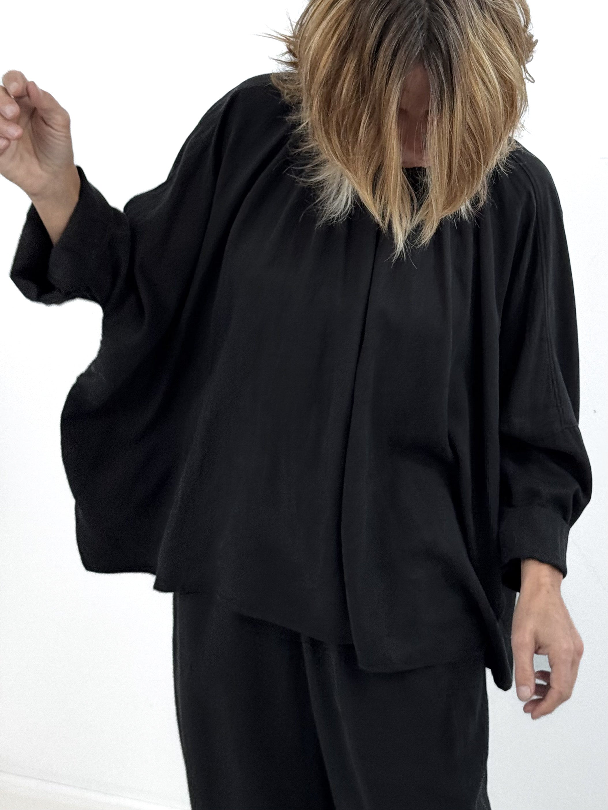 Person wearing a loose-fitting black outfit on a white background