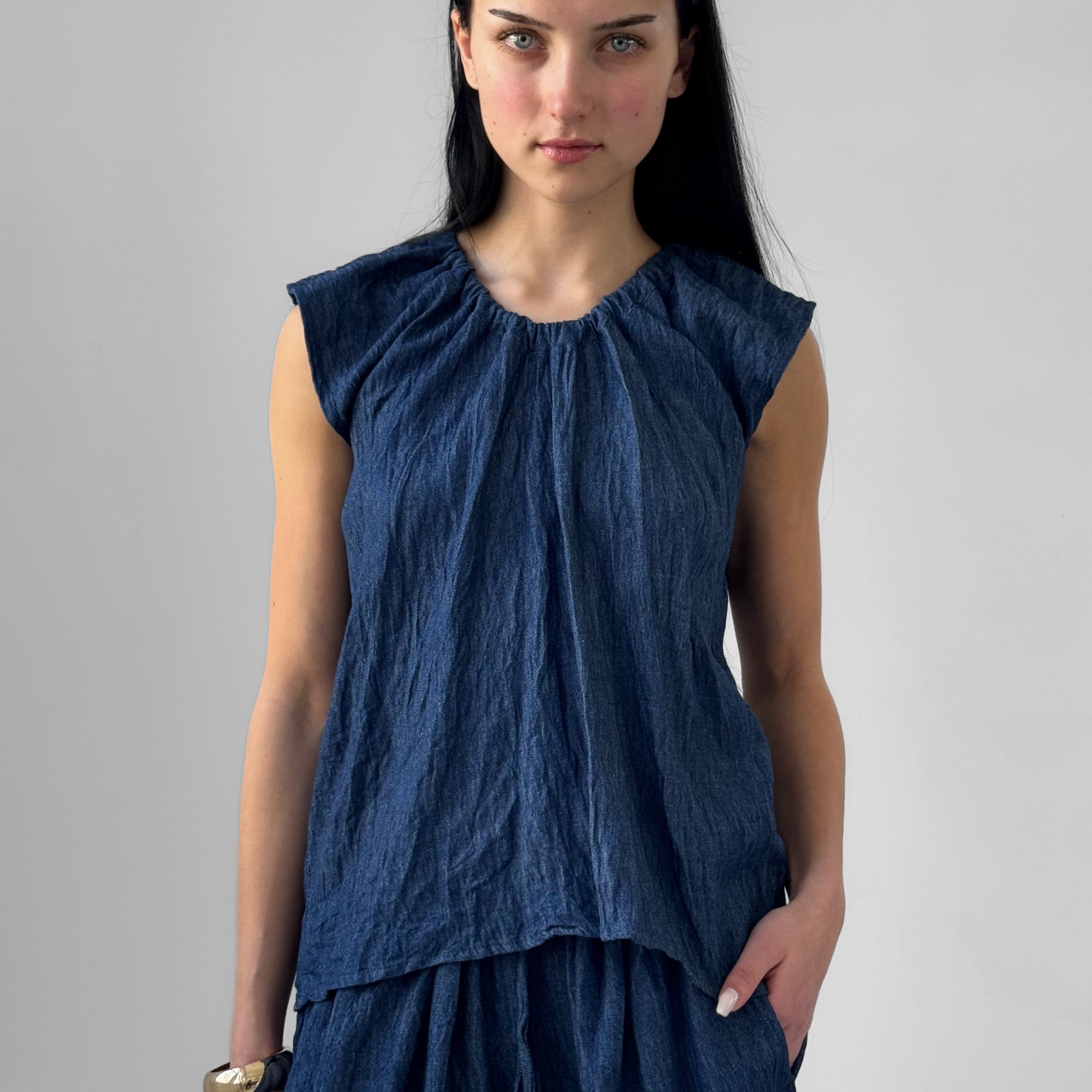 Woman wearing a blue sleeveless top and skirt against a gray background