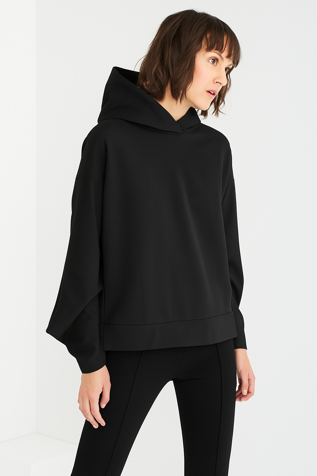 Woman wearing a black hooded top against a white background