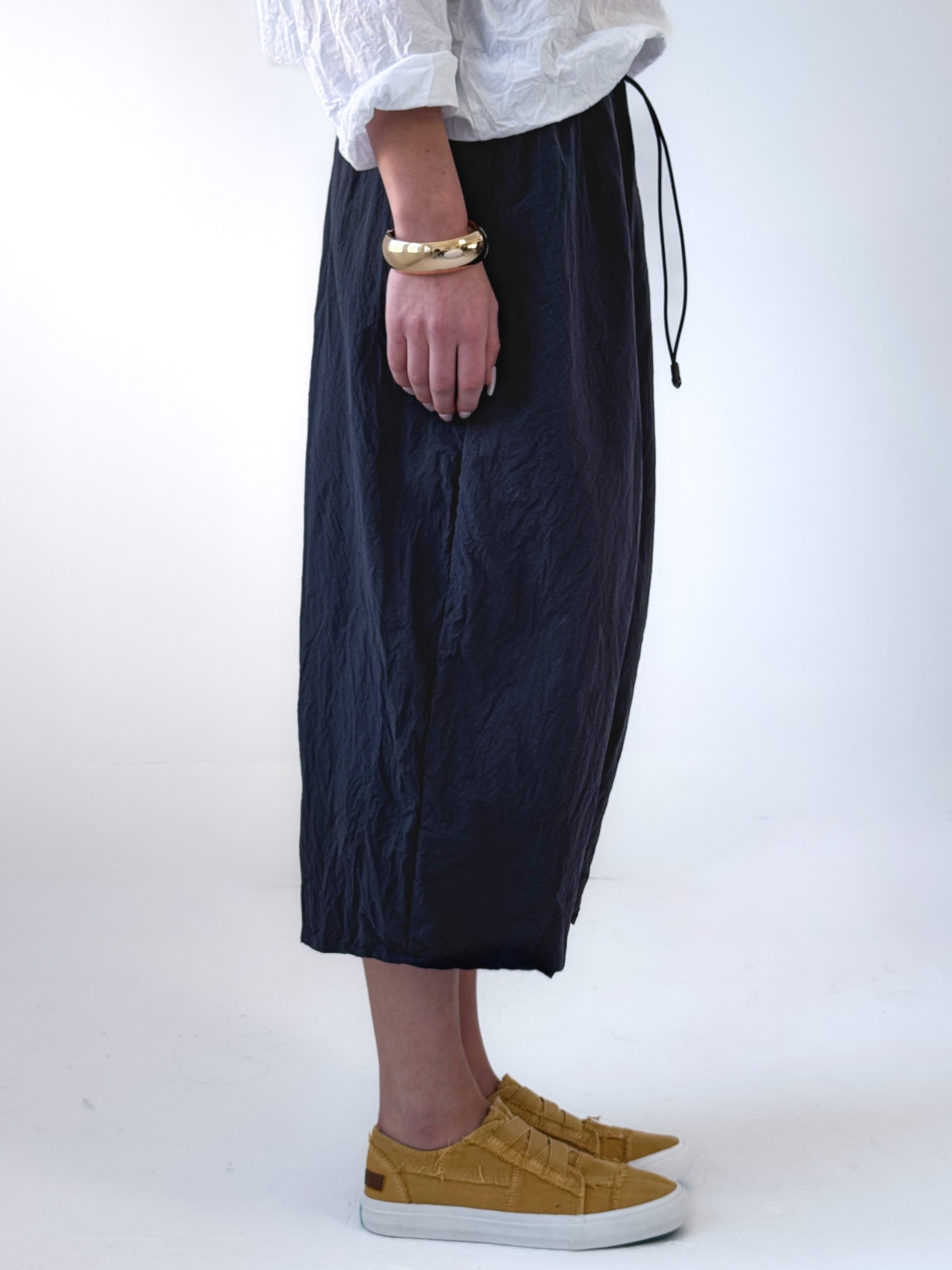 Noor drop crotch pants in crumpled black cotton with drawstring waist and relaxed cropped silhouette