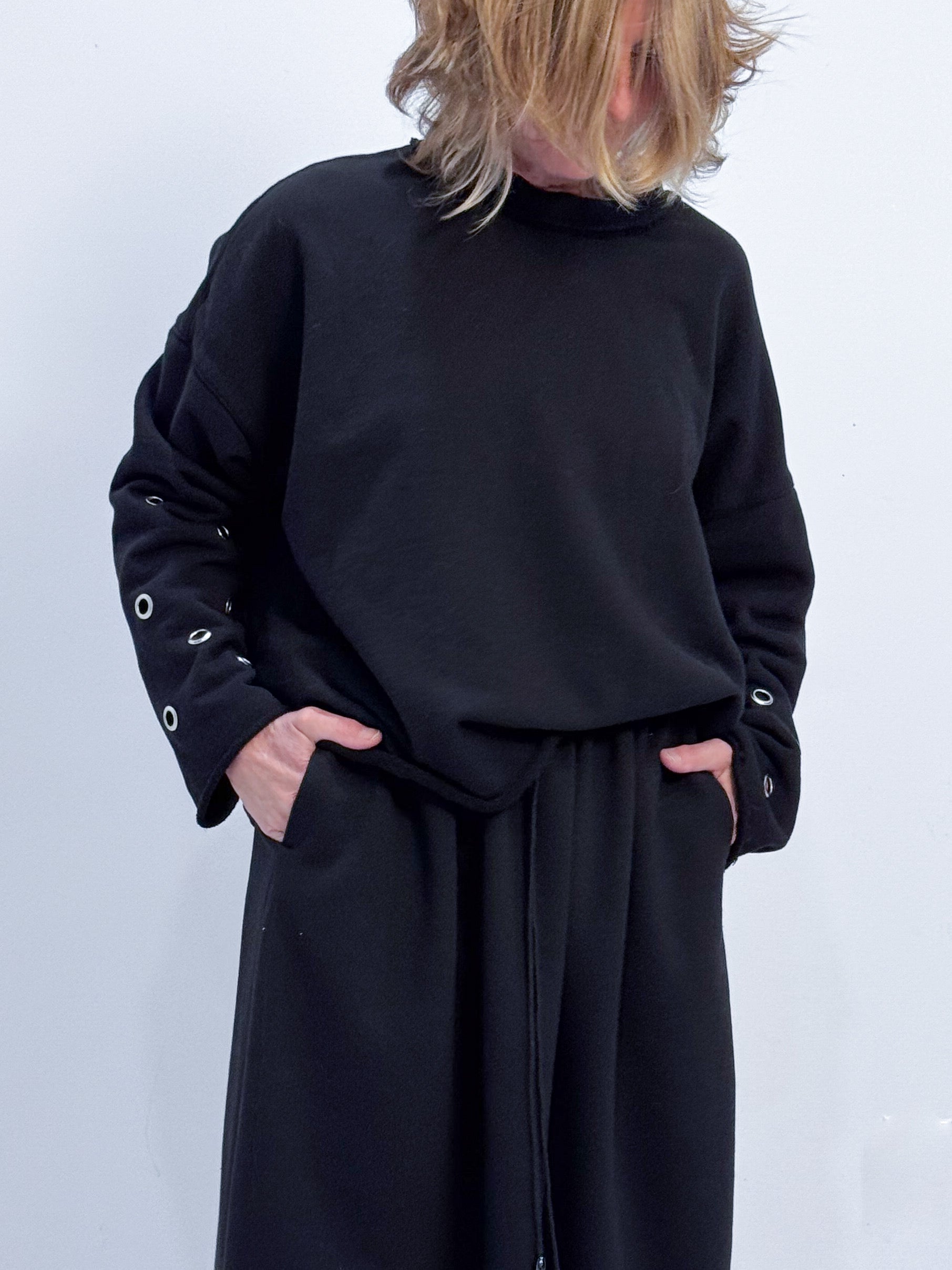 Person wearing a black outfit with a plain background