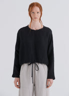 Person wearing a black sweater and light gray pants on a white background