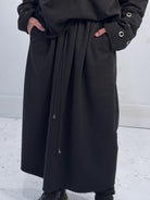 Person wearing a long black coat with a white background