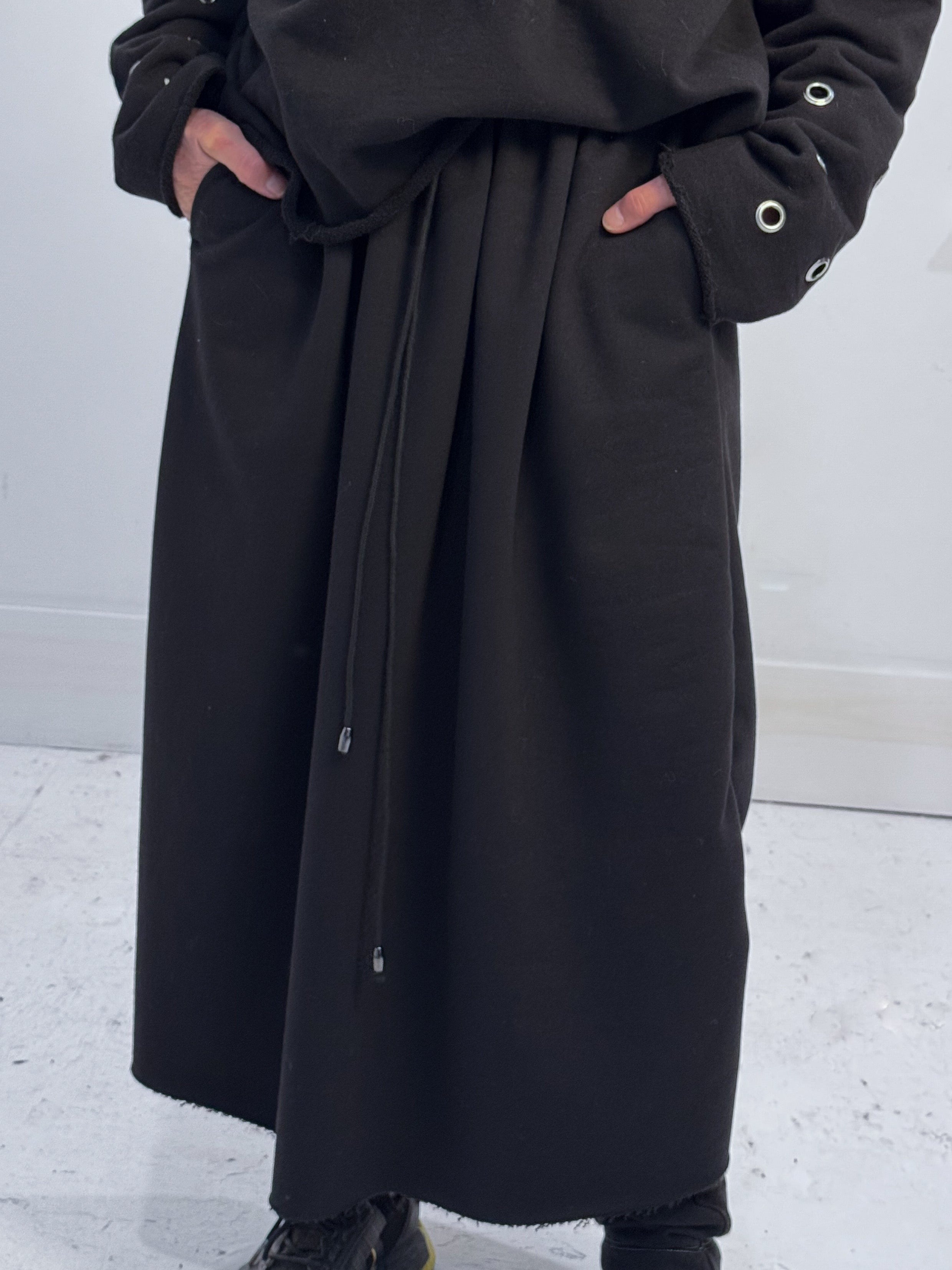 Person wearing a long black coat with a white background