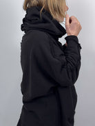 Person wearing a black hoodie against a plain background