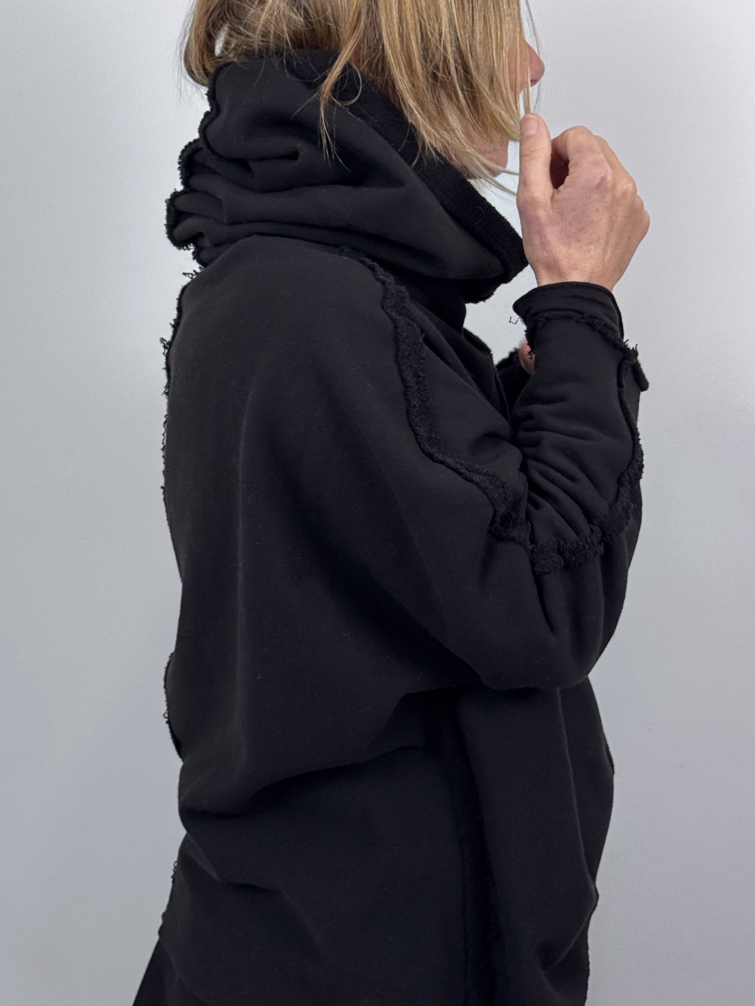 Person wearing a black hoodie against a plain background