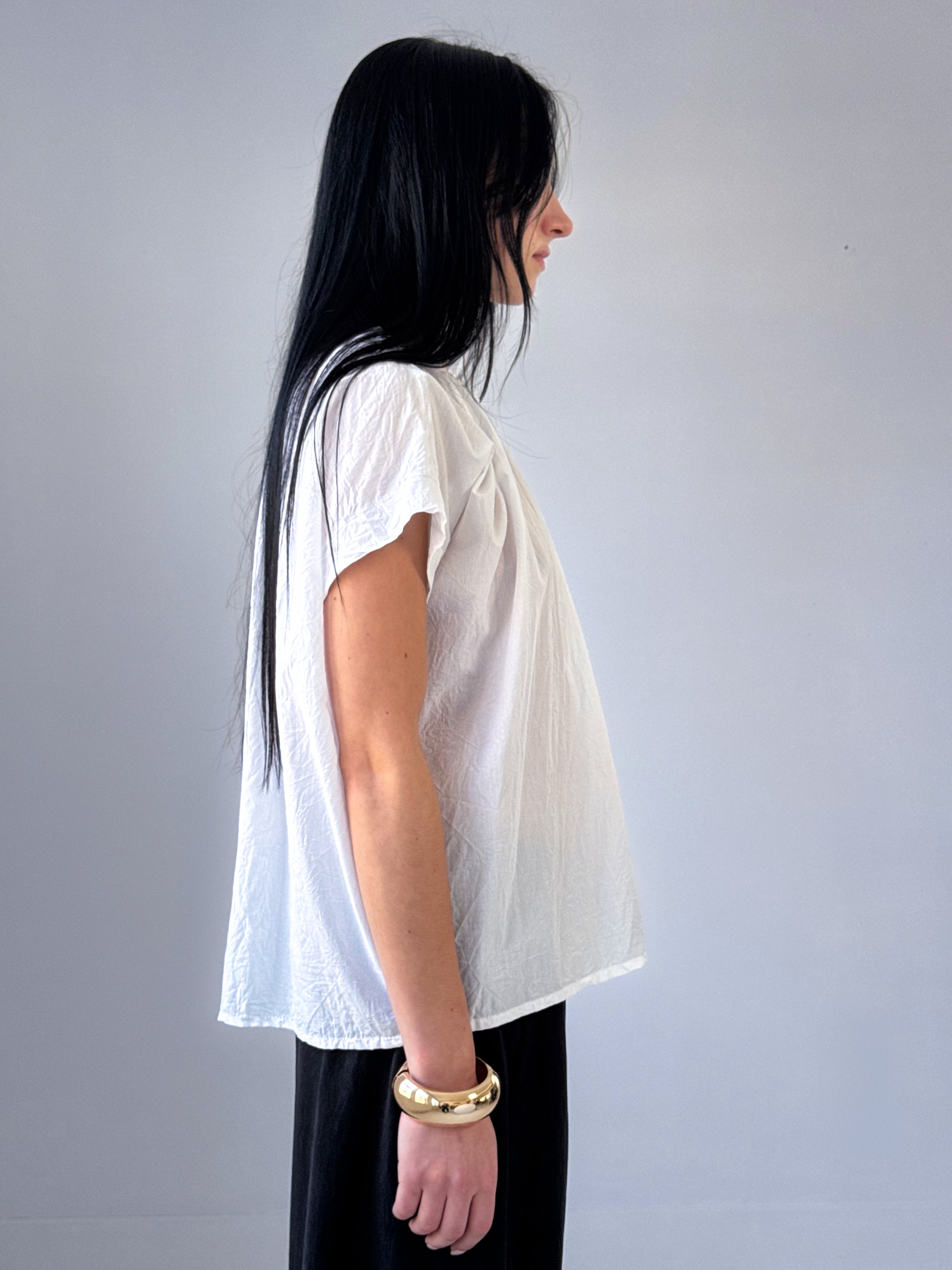 Person wearing a white t-shirt and dark pants against a plain background