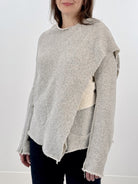 Woman wearing a gray and white wrap jacket against a white background