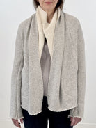 Woman wearing a gray and white wrap jacket against a white background