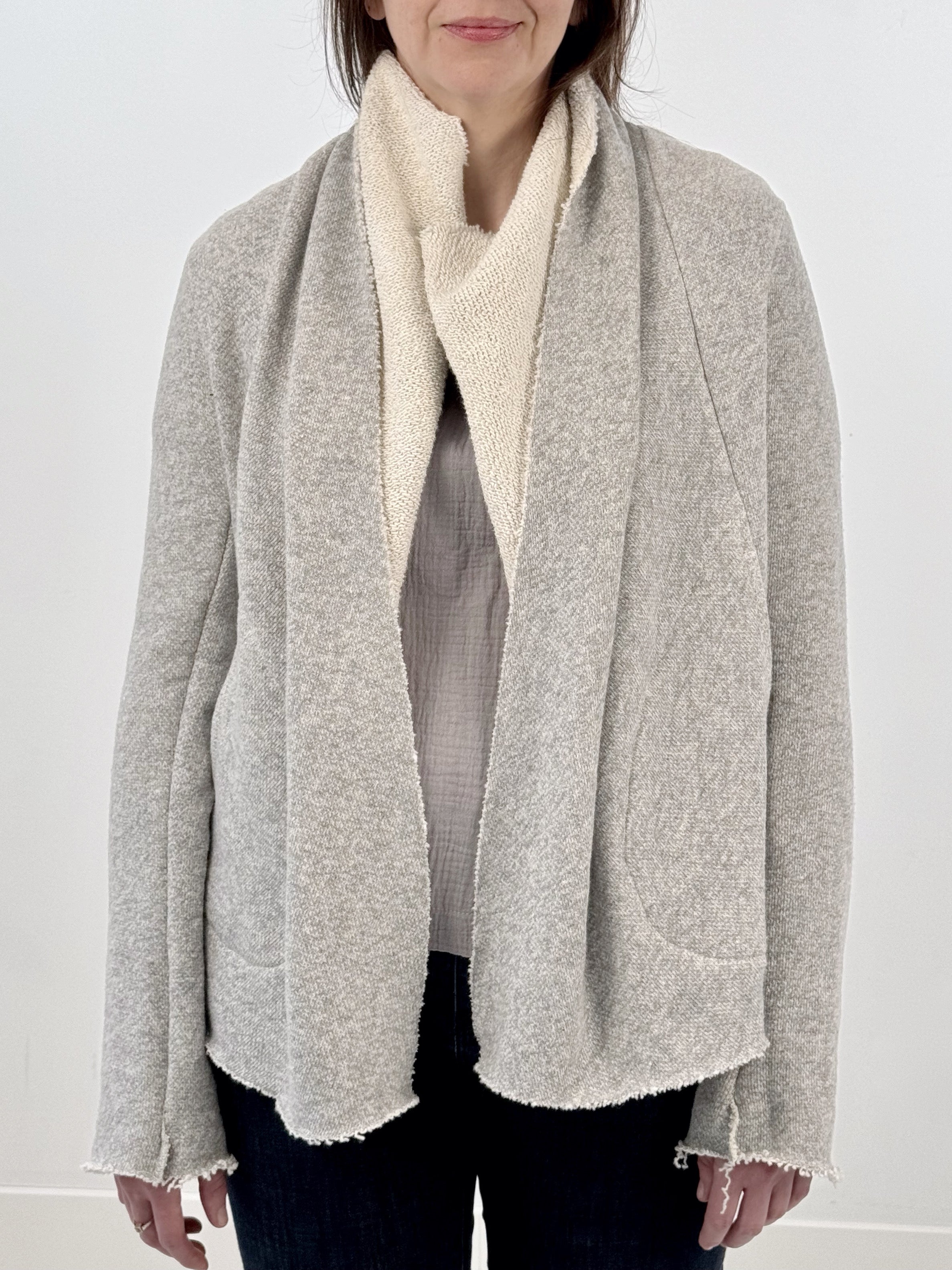 Woman wearing a gray and white wrap jacket against a white background