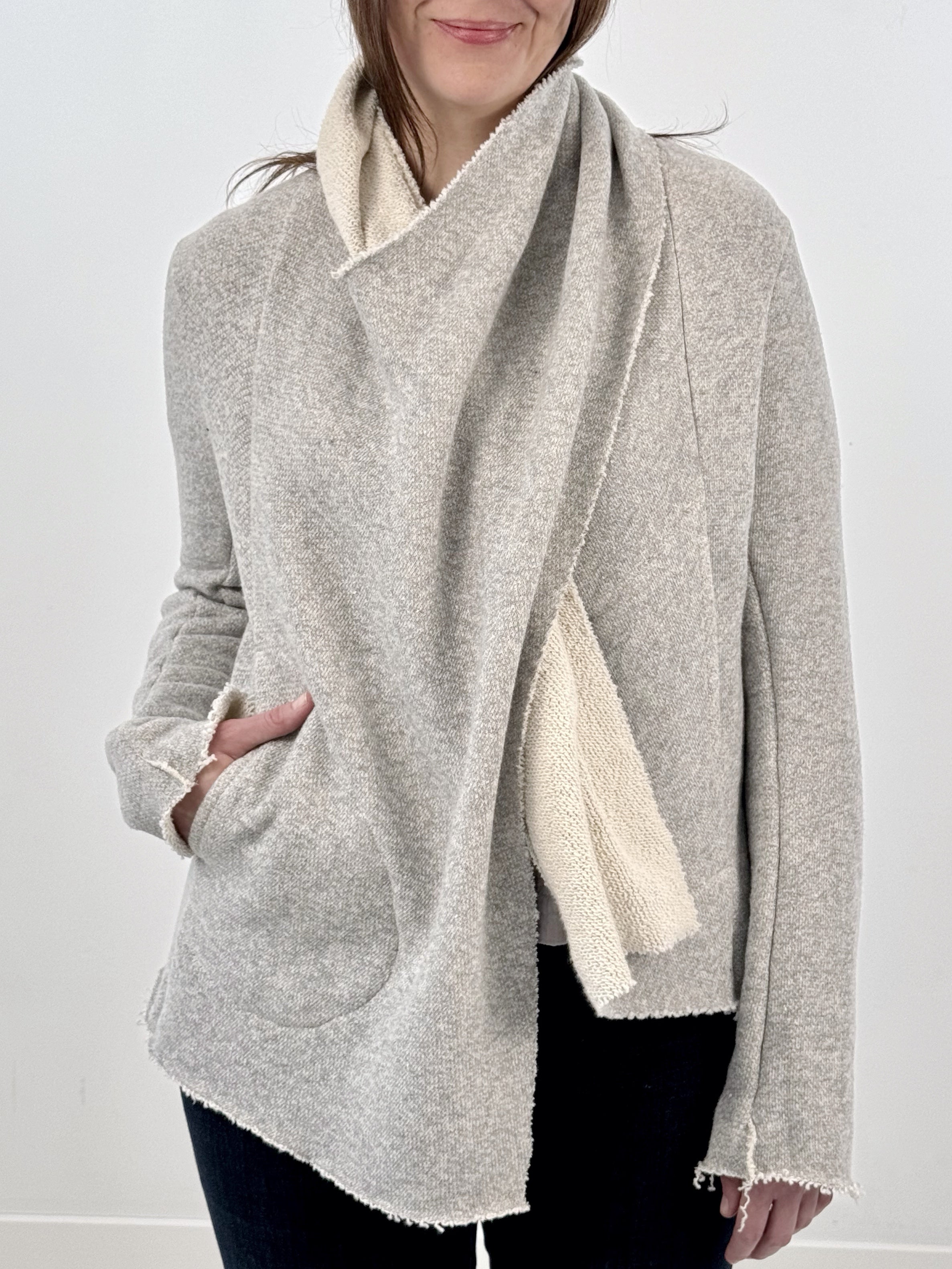 Woman wearing a gray and white wrap jacket against a white background