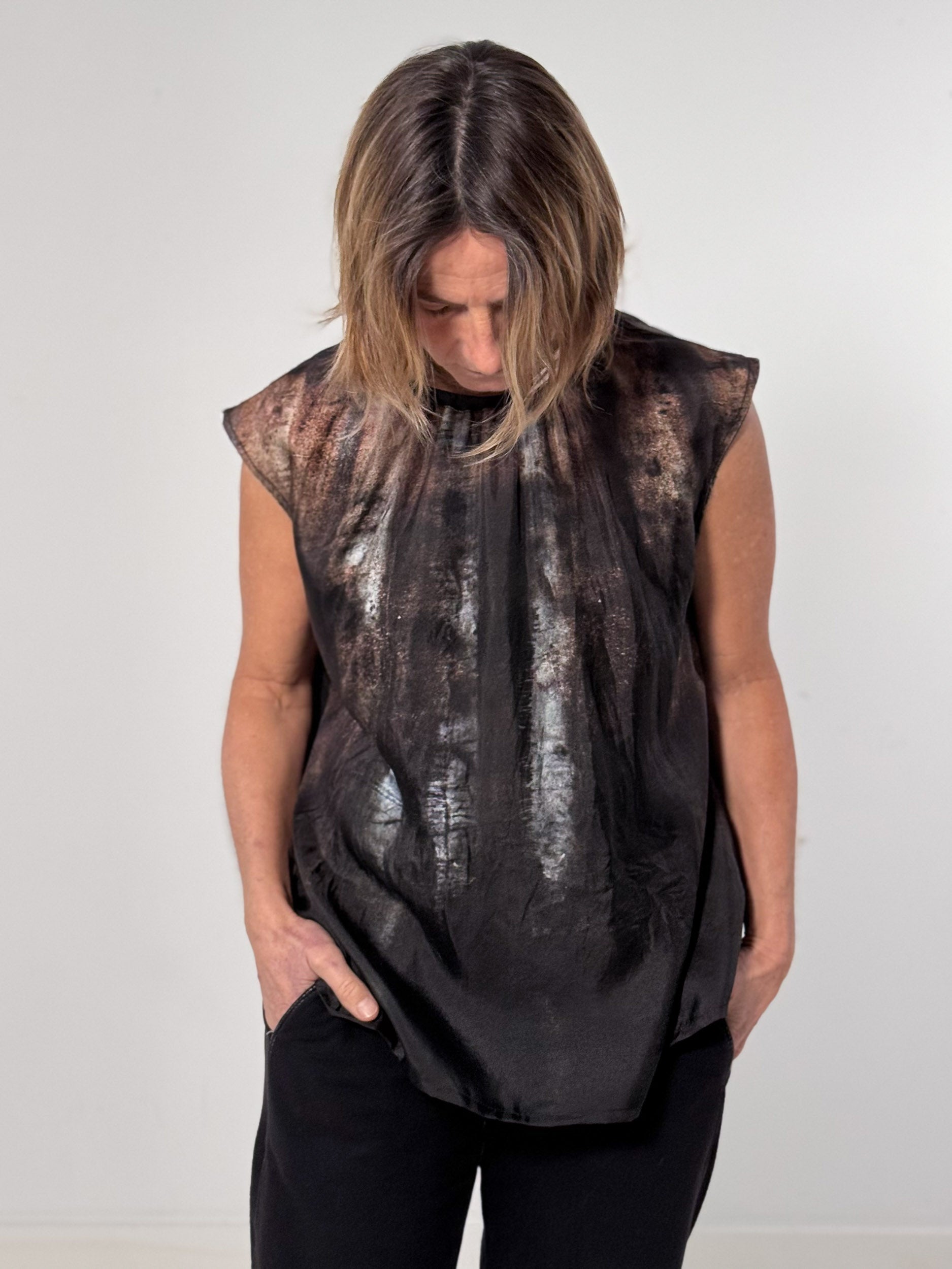 Person wearing a sleeveless black top with a textured pattern on a white background