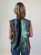 Person wearing a sleeveless, multicolored top with a white background