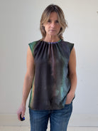 Woman wearing a sleeveless, multicolored top against a plain background