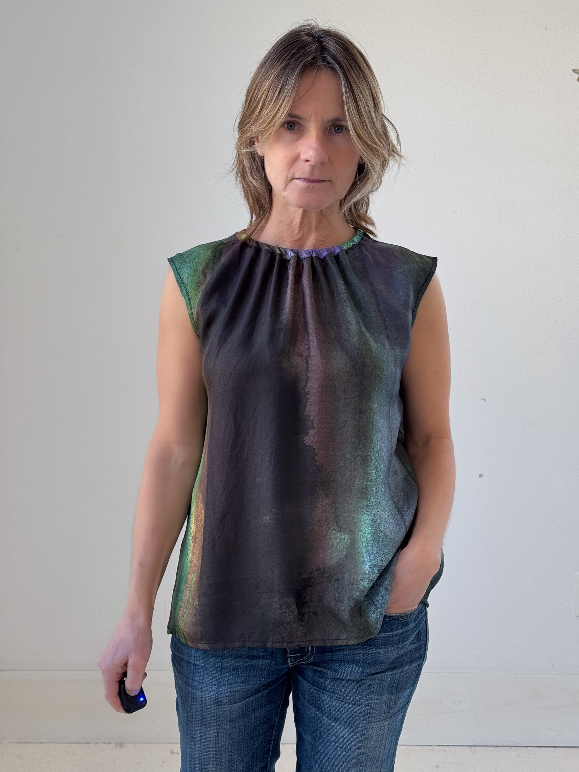 Woman wearing a sleeveless, multicolored top against a plain background