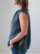 Person wearing a sleeveless, multicolored top against a plain background