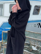 Person wearing a black hoodie in front of a boat